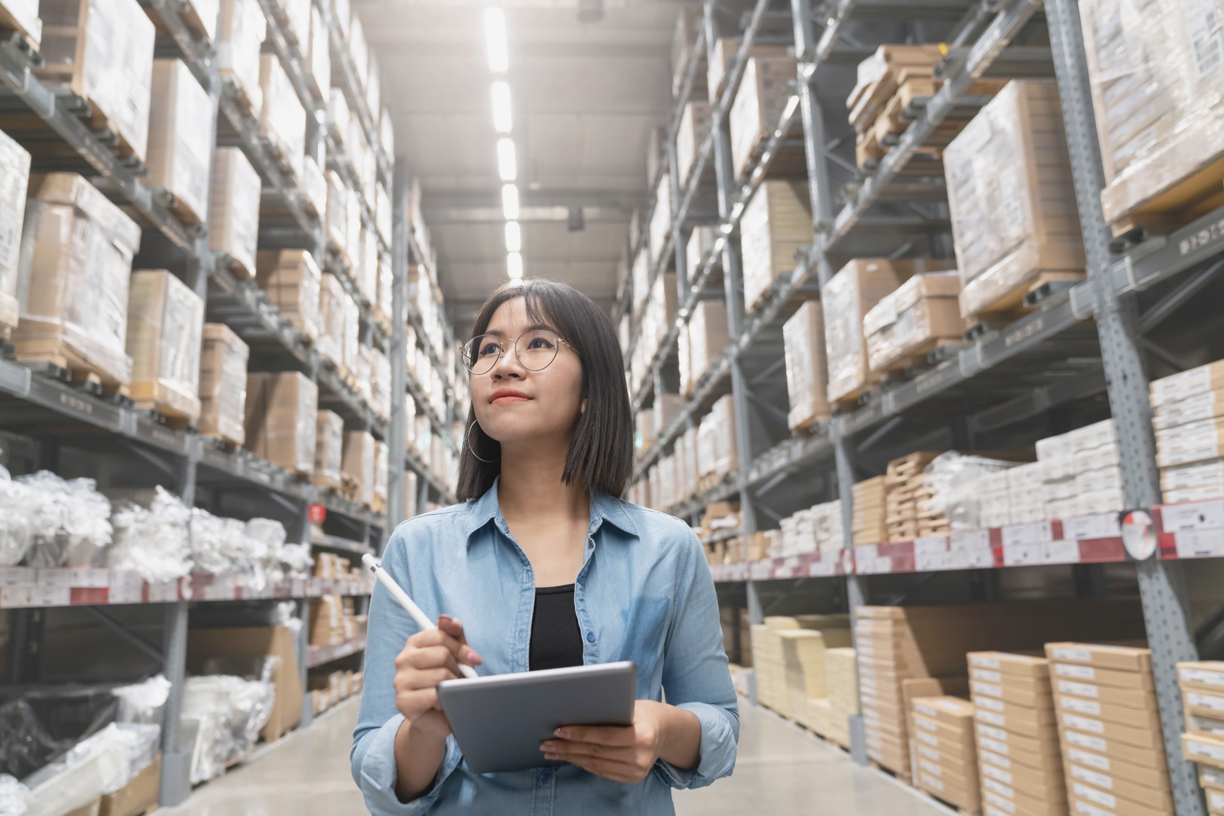 Woman performing audit in warehouse with quality audit software on ipad for compliance audit