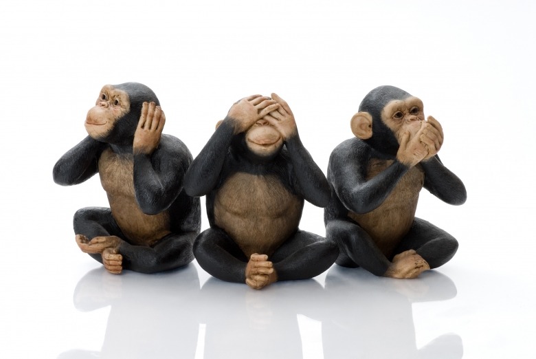 Three monkeys, one with hands over ears, one with hands over eyes and one with hands over mouth in hear, see and speak no evil pose