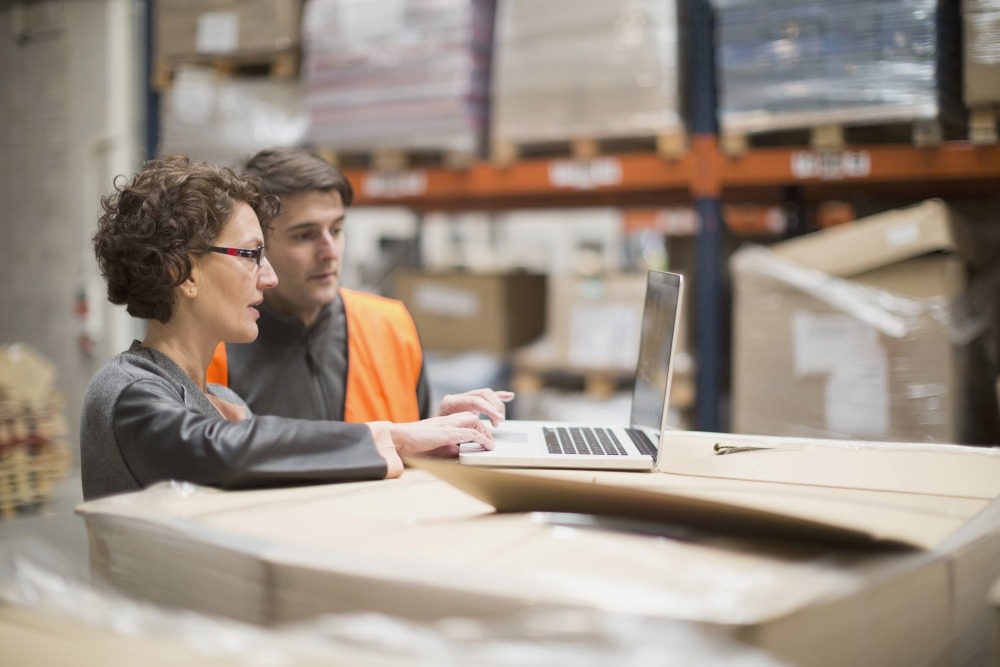 Two quality managers in warehouse working with ETQ Reliance supply chain management software