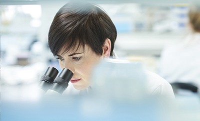 Female lab scientist using microscope