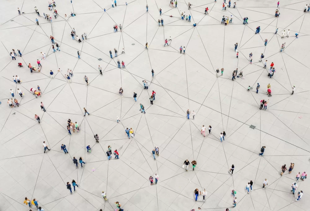 Aerial view of people walking around connected with lines to convey a network. An EQMS system helps make connections between the people and data in your organization.
