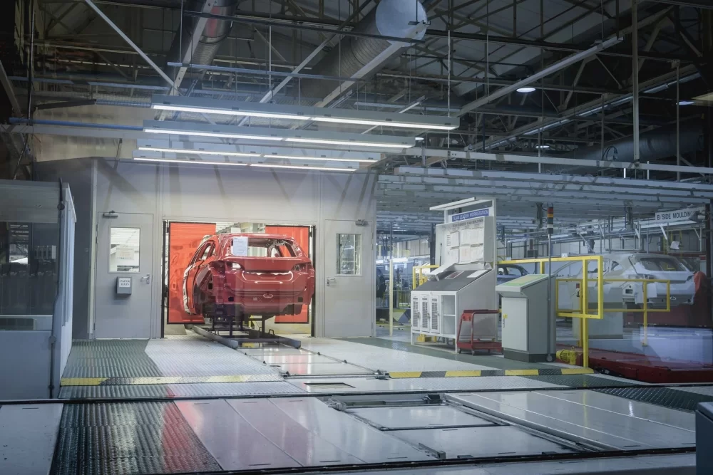 Red automobile body on factory assembly line